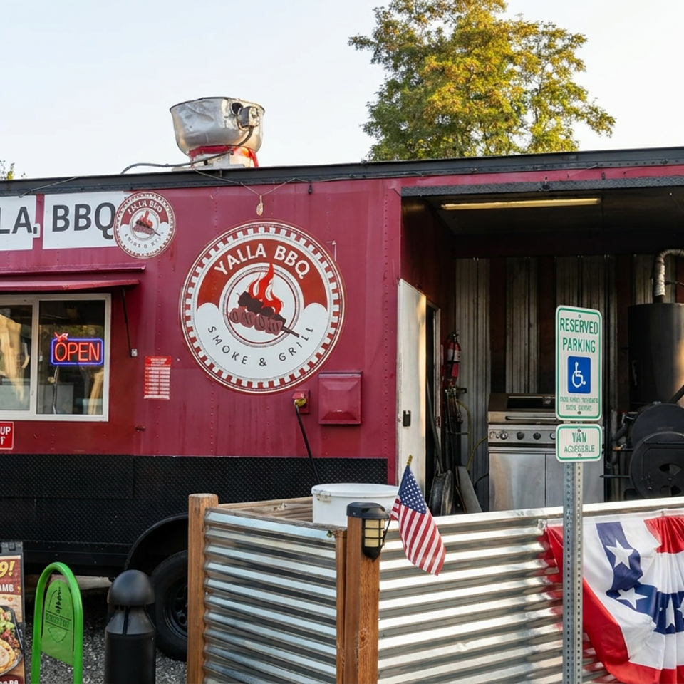 Yalla BBQ food truck with open service window, smoker, American bunting, and outdoor seating area surrounded by trees.